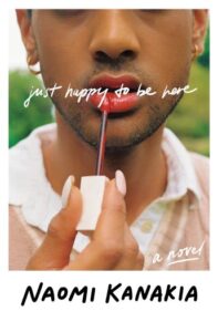 Photographic cover for Just Happy to Be Here. The photo is a close up but is cropped so that only the lower half of this trans girl's face, her neck, and a bit of her shoulders are visible. She has medium brown skin, black stubble, gold hoop earrings, and either white or light pink long manicured nails. She is wearing a collared shirt with a sweater over it, and she is applying red lipgloss.