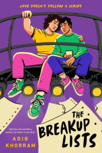 Cover of the book The Breakup Lists. Two young men are sitting on the top of stage lights that are on and aimed down at the stage. One has his arm around the other. They are wearing brightly colored clothing and the background is purple. The one being hugged is holding a notebook and there are quite a few pieces of paper fluttering down below their shoes.