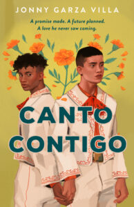 The cover of the book Canto Contigo. Two young men are wearing white Mariachi suits with orange trim. They are holding hands and standing back to back. The one on the left has dark short curly hair. The one on the right has dark hair in a buzz cut. There are orange flowers in the air above their heads. 