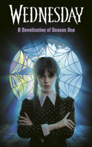 Cover for Wednesday: A Novelization of Season One. Wednesday Addams stands staring straight at the viewer with her arms crossed. She appears to be in a dark attic space, but there is a spideweb design circular window behind her with light streaming through it and backlighting her. She has her hair in two pigtail braids and is wearing a black dress with a large white collar. 