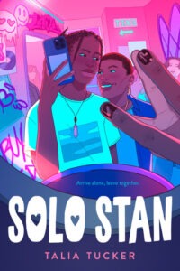 Illustrated cover for Solo Stan. The cover is framed like it is a crowded graffitied concert bathroom selfie, with two Black teenagers standing close together and looking positively at each other as the selfie is taken. In small letters at the bottom, it says "Arrive alone, leave together."