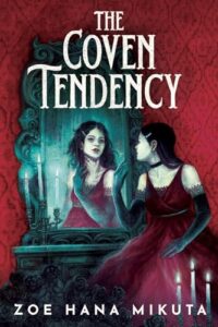 Cover of the book The Coven Tendency. A young woman is sitting in front of a vanity with mirror. She has dark hair and pale skin. She is wearing a red dress and there is red wallpaper. There is a candelabra with three white candles burning.