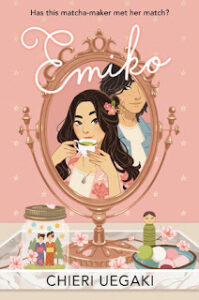 The book cover of Emiko shows a young woman sipping green tea and a young man watching her over her shoulder. This is an image that is seen through a mirror on a stand on a tray on a table. On the tray there are also cherry blossoms and a mason jar that has  two tiny people in kimonos. There is also a dish with what may be fruit or candies on a skewer. 