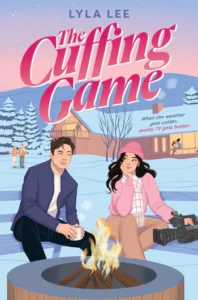 The cover of the book The Cuffing Game by Lyla Lee has two young people sitting by a fire in a fire pit surrounded by snow. They're smiling slightly while staring at each other. The young man has short dark hair and is holding a mug of something that is steaming. The young woman is dressed in pink and has long wavy dark hair. She also has a large video camera at her side. There is a building behind them with people inside. There is a hill and the sky is pink and purple behind the building.
