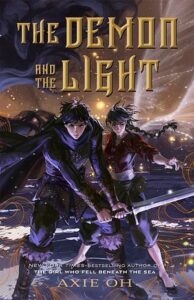 The cover of the demon and the light. There is a young man and young woman in dark clothing in a defensive stance. The young man is holding a sword and has a cape. It is dark with some lights in the background.