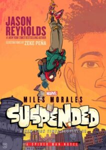 Illustrated cover of Miles Morales Suspended by Jason Reynolds. The background is an orange and yellow sky With a person hanging from a rope tied around his ankle. He has his arms crossed and looks unbothered. There is a cityscape below him. 