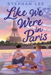 Book cover for Like We Were in Paris. Two young men are sitting on a blanket with baguettes, cheese, fruit and other items. One has short dark hair and the other has light hair. The Eiffel Tower is in the distance.