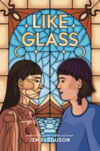The book cover of Like Glass by Jen Ferguson is created in the style of a stained glass window. There are two people with light brown skin and dark hair staring into the other person's eyes. The one on the left has long straight hair and is in parts like stained glass also. The one on the right is more realistic and has short straight hair and long dark earrings. The background is a picture with browns and blues. There is a sky and then water at the bottom and some mountains in between the blues.